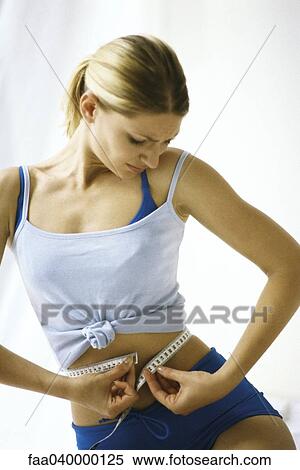 Woman in sports clothing, measuring waist View Large Photo Image Stock Photography - Woman in sports clothing, measuring waist. Fotosearch