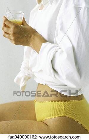 Woman in underwear holding cup of orange juice, mid section, side view View Large Photo Image Stock Image - Woman in underwear holding cup of orange juice, mid section, side view. Fotosearch