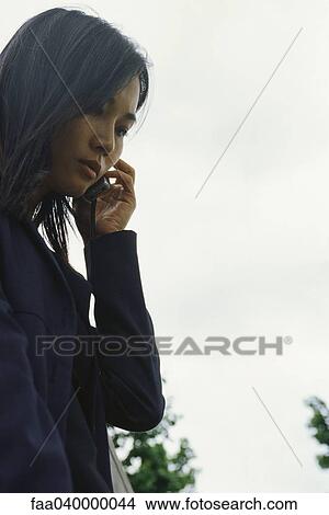 Woman using cell phone outdoors, low angle view View Large Photo Image Picture - Woman using cell phone outdoors, low angle view. Fotosearch