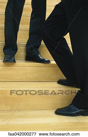 Stock Photo - "Businessmen standing on steps, low-section". Fotosearch