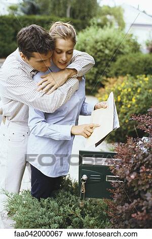 "Couple checking mail together, man embracing woman from behind" View Large Photo Image Stock Photo - "Couple checking mail together, man embracing woman from behind". Fotosearch
