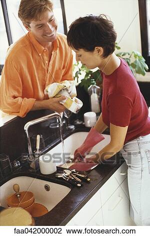 Couple doing dishes together at kitchen sink View Large Photo Image Stock Image - Couple doing dishes together at kitchen sink. Fotosearch