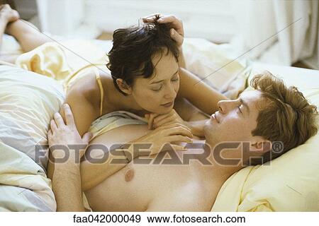 "Couple lying in bed together, woman resting on man's chest" View Large Photo Image Stock Photo - "Couple lying in bed together, woman resting on man's chest". Fotosearch