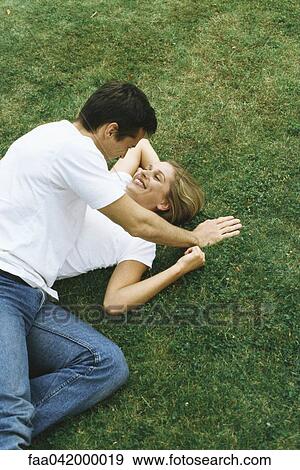 Stock Photo - "Couple lying together on ground, high angle view". Fotosearch