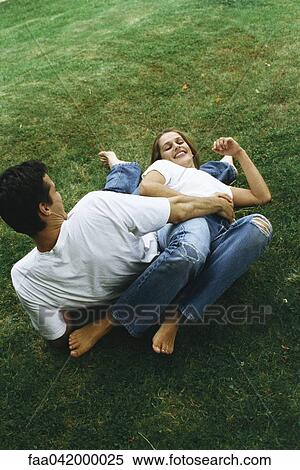 "Couple reclining on ground together, laughing, high angle view" View Large Photo Image Stock Photography - "Couple reclining on ground together, laughing, high angle view". Fotosearch