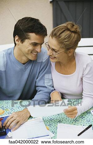 Stock Image - "Couple sitting at table, discussing finances". Fotosearch