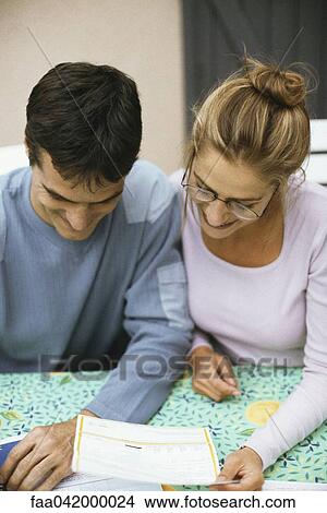 "Couple sitting at table, paying bills" View Large Photo Image Picture - "Couple sitting at table, paying bills". Fotosearch
