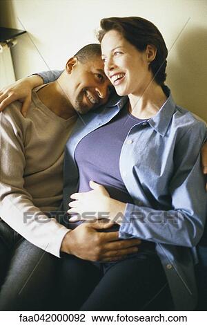 "Couple sitting together, with hands on woman's pregnant belly" View Large Photo Image Stock Image - "Couple sitting together, with hands on woman's pregnant belly". Fotosearch