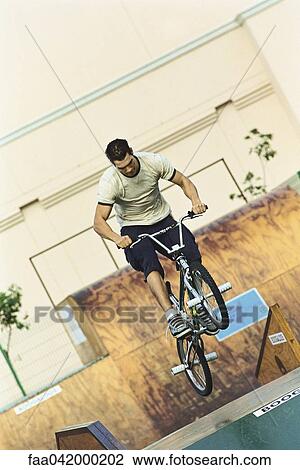 Stock Image - Cyclist doing midair trick at skatepark. Fotosearch