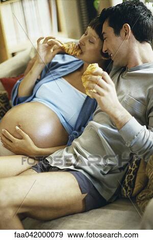 "Expecting couple sitting together on sofa, eating croissants" View Large Photo Image Stock Photo - "Expecting couple sitting together on sofa, eating croissants". Fotosearch