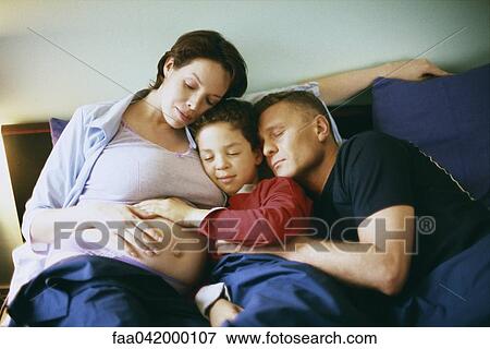 "Family together in bed, boy placing hand on woman's pregnant stomach" View Large Photo Image Stock Photo - "Family together in bed, boy placing hand on woman's pregnant stomach". Fotosearch