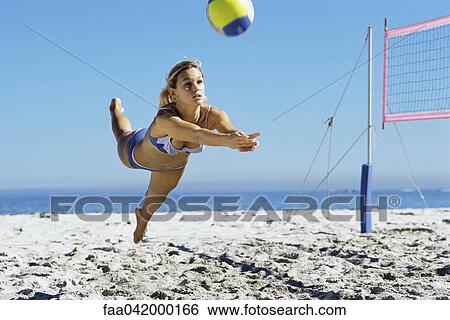 Stock Photograph - "Female playing beach volleyball, diving to catch ball". Fotosearch