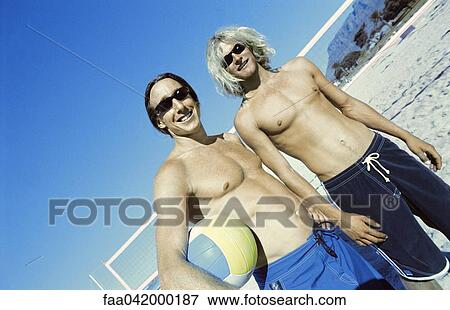 Stock Photo - Friends at beach preparing to play beach volleyball. Fotosearch