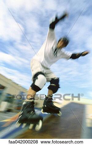 Inline skater with arms raised sliding on ramp at skatepark View Large Photo Image Stock Photo - Inline skater with arms raised sliding on ramp at skatepark. Fotosearch