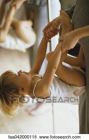 "Little girl holding mother's hands, turning flip against her stomach" View Large Photo Image Stock Photography - "Little girl holding mother's hands, turning flip against her stomach". Fotosearch