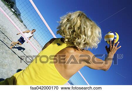 Stock Image - Male playing beach volleball preparing to hit ball. Fotosearch