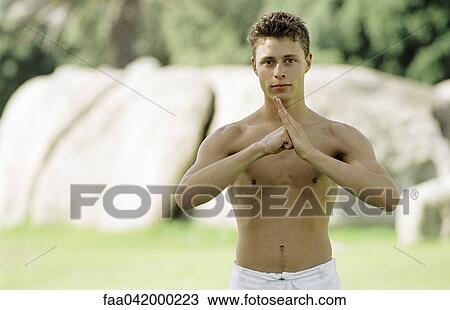 Stock Image - "Male practicing martial arts in park setting, front view". Fotosearch