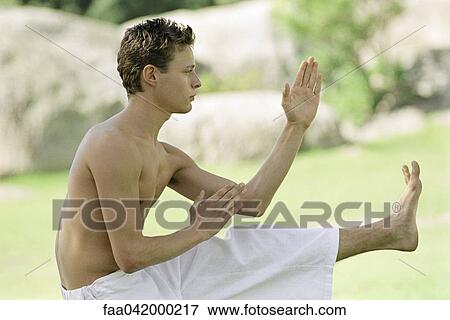 Stock Photo - "Male practicing martial arts in park setting, side view". Fotosearch