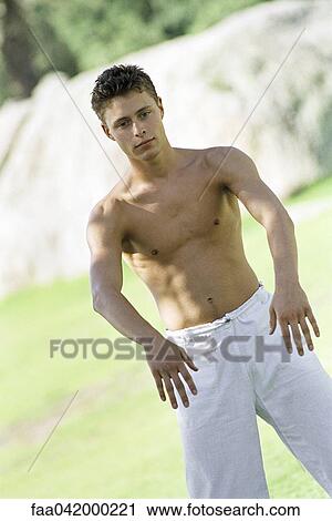 Stock Image - "Male practicing tai chi chuan in park setting, front view". Fotosearch