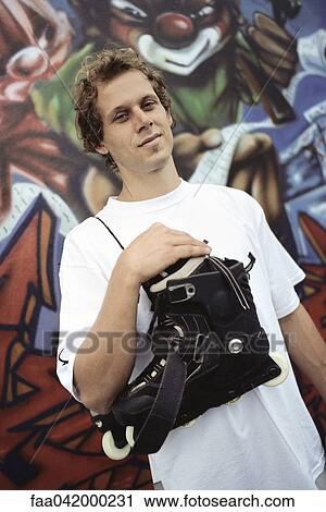 Male with pair of inline skates hanging over shoulder standing in front of wall mural View Large Photo Image Stock Image - Male with pair of inline skates hanging over shoulder standing in front of wall mural. Fotosearch