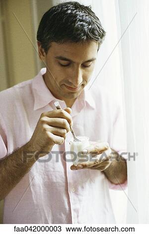 Man eating yogurt View Large Photo Image Stock Image - Man eating yogurt. Fotosearch
