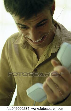 "Man gripping phone receiver, grimacing" View Large Photo Image Picture - "Man gripping phone receiver, grimacing". Fotosearch