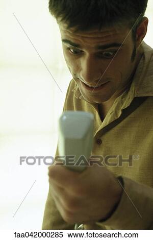 Stock Photography - "Man gripping phone receiver, staring with look of astonishment". Fotosearch
