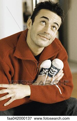 "Man holding baby shoes, looking up and smiling" View Large Photo Image Stock Photo - "Man holding baby shoes, looking up and smiling". Fotosearch