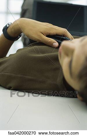 Stock Image - "Man napping with laptop computer on lap, close-up, cropped view". Fotosearch