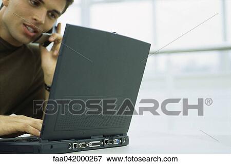 Stock Photo - "Man phoning, using laptop computer, low angle view". Fotosearch