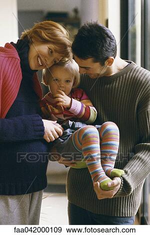 Stock Photo - "Parents holding little girl, smiling". Fotosearch