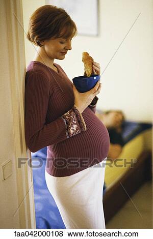 "Pregnant woman leaning in doorway, eating croissant" View Large Photo Image Stock Photo - "Pregnant woman leaning in doorway, eating croissant". Fotosearch