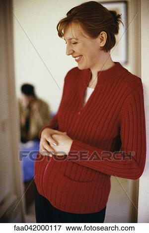"Pregnant woman leaning in doorway with hands on stomach, smiling" View Large Photo Image Stock Photo - "Pregnant woman leaning in doorway with hands on stomach, smiling". Fotosearch