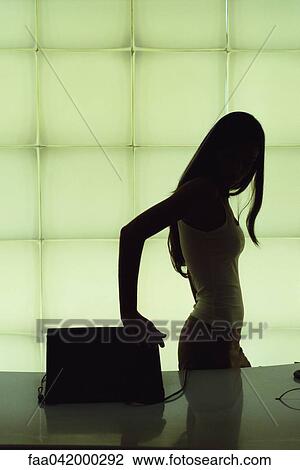 Stock Image - Silhouette of woman closing laptop computer. Fotosearch