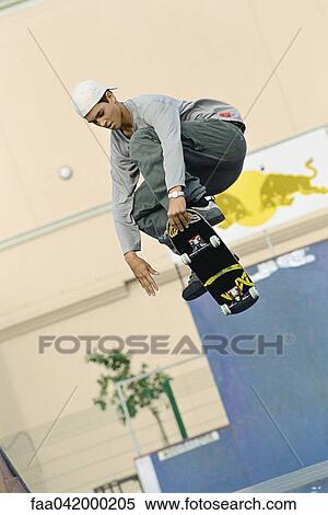 Stock Photography - Skateboarder doing midair trick at skatepark. Fotosearch