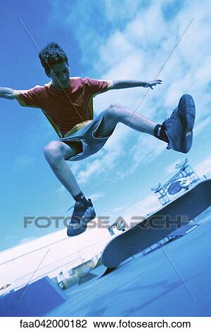 "Skateboarder doing trick in midair, low angle view" View Large Photo Image Stock Image - "Skateboarder doing trick in midair, low angle view". Fotosearch