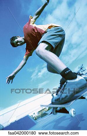 Stock Image - "Skateboarder doing trick, low angle view". Fotosearch