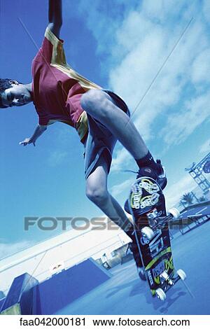 Stock Image - "Skateboarder doing trick, low angle view". Fotosearch