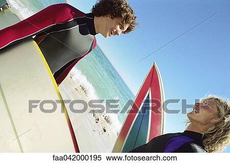 Stock Photography - Surfers on beach having conversation. Fotosearch