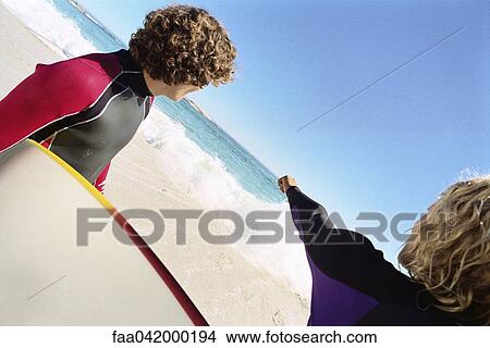 Picture - "Surfers on beach, one pointing to distance offshore". Fotosearch