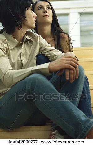 Stock Image - "Two females sitting together on stairs, both looking away". Fotosearch