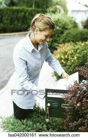 Stock Image - "Woman checking mail, smiling". Fotosearch