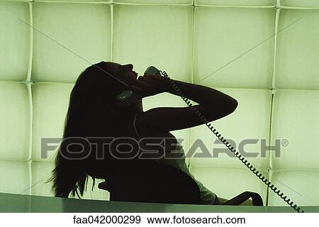 Stock Photo - "Woman phoning, leaning back in chair laughing". Fotosearch