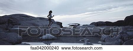 Woman running across footbridge near seashore in early morning View Large Photo Image Stock Image - Woman running across footbridge near seashore in early morning. Fotosearch