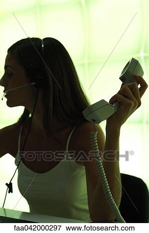 "Woman wearing headset, holding phone receiver" View Large Photo Image Stock Photo - "Woman wearing headset, holding phone receiver". Fotosearch