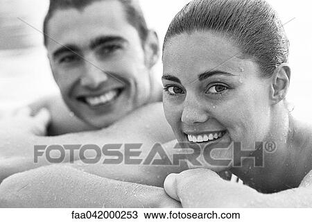 Stock Image - "Young couple resting heads on arms, wet, portrait". Fotosearch