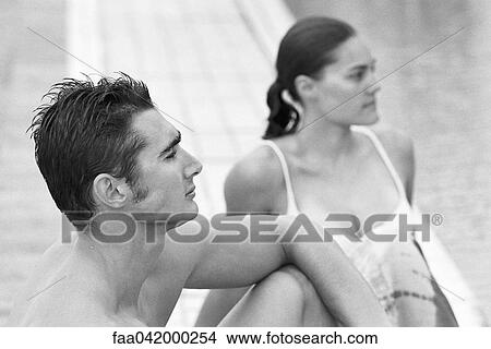 Young couple sitting together at poolside both looking away View Large Photo Image Picture - Young couple sitting together at poolside both looking away. Fotosearch