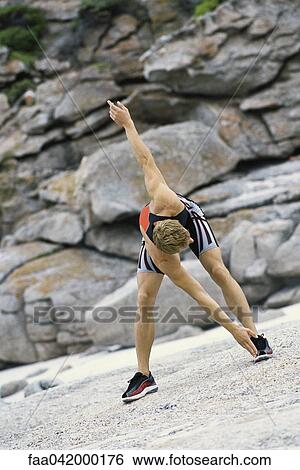 Young man bending forward touching toes outdoors View Large Photo Image Stock Photograph - Young man bending forward touching toes outdoors. Fotosearch