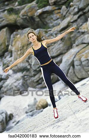 Stock Image - Young woman doing jumping jacks outdoors. Fotosearch