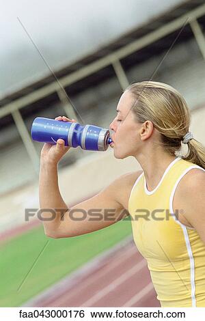 Stock Photograph - Athletic woman drinking water from bottle. Fotosearch